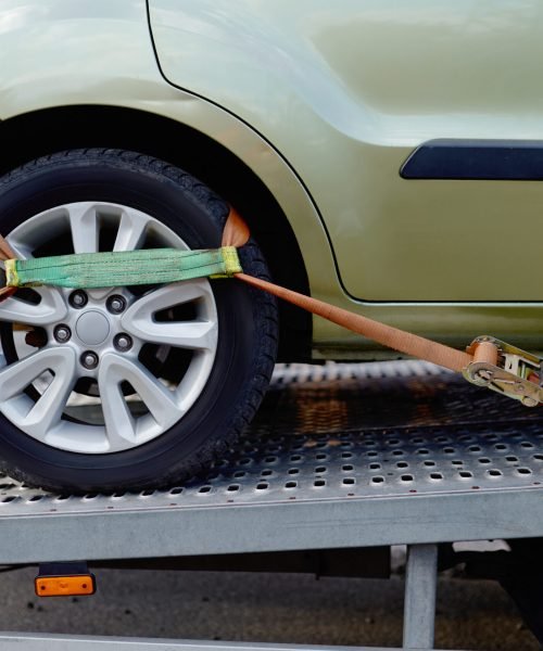 Car wheel fixing tow truck mechanism with belt in platform to protect from moving. Cropped shot