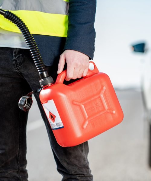 Man with refuel canister on the roadside with his car on the background, close-up view with no face